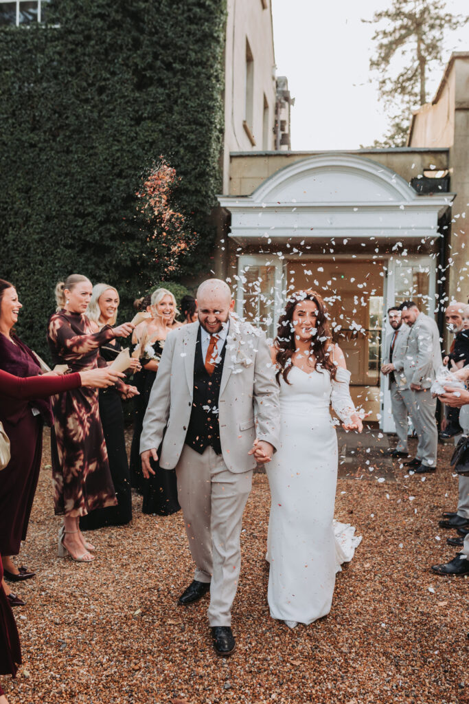 bride and groom walking through confetti at at northbrook park wedding