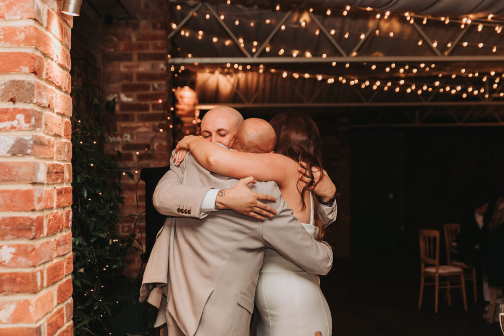 bride, groom and father of the bride hugging after speeches