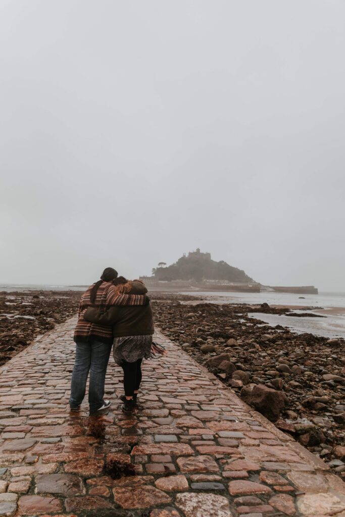 two women holding eachother on marazion beach