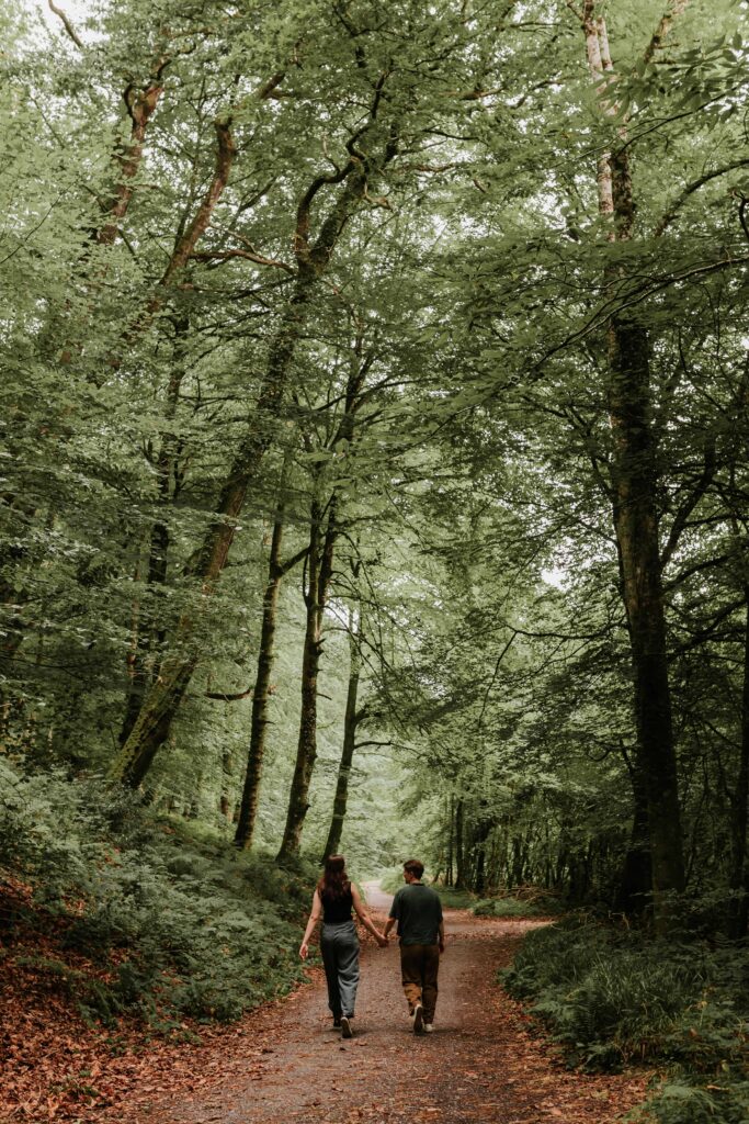couple walking through dense trees in devon woodland