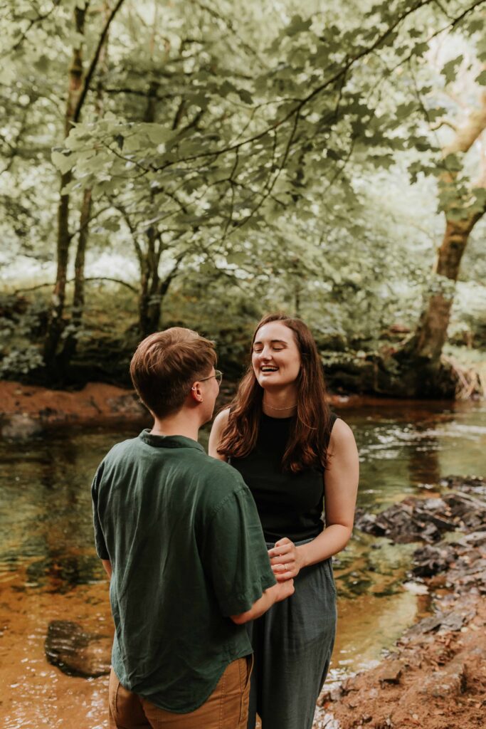 couple laughing looking at each other in devon woodland