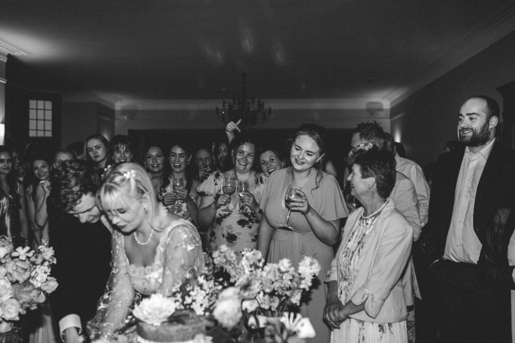 b&w photo of bride and groom with guests watching taken by wedding photographer in hampshire