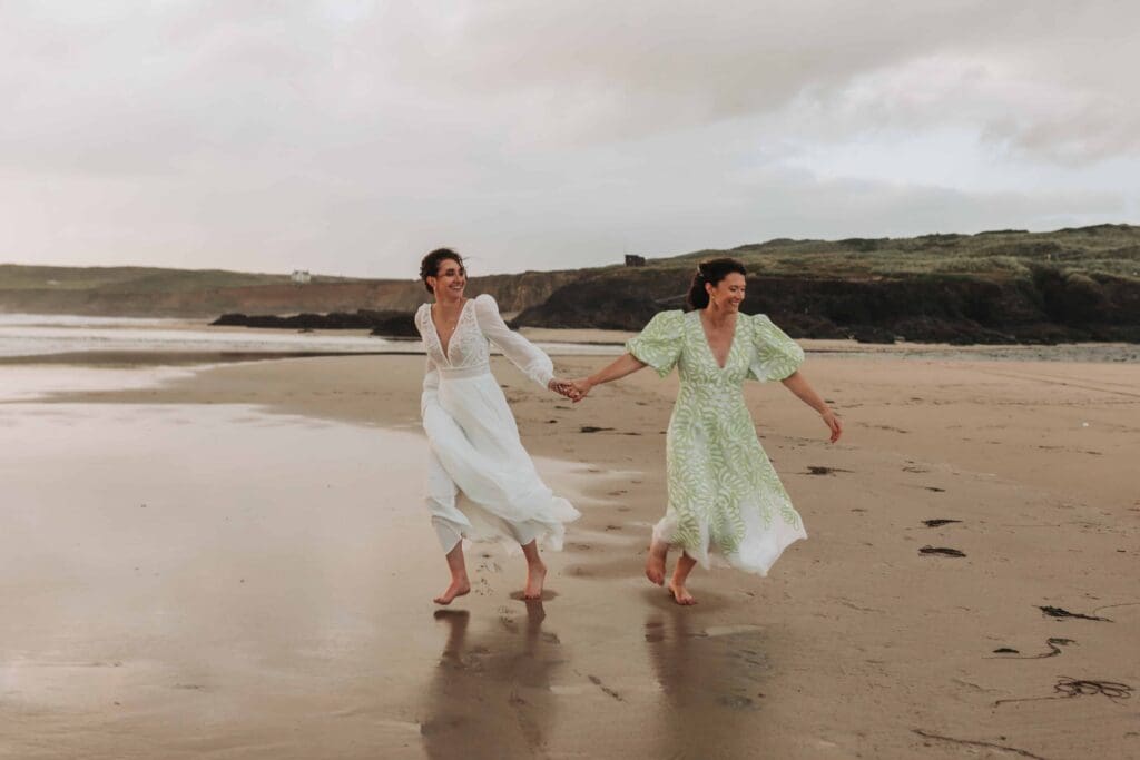 two brides running across the beach