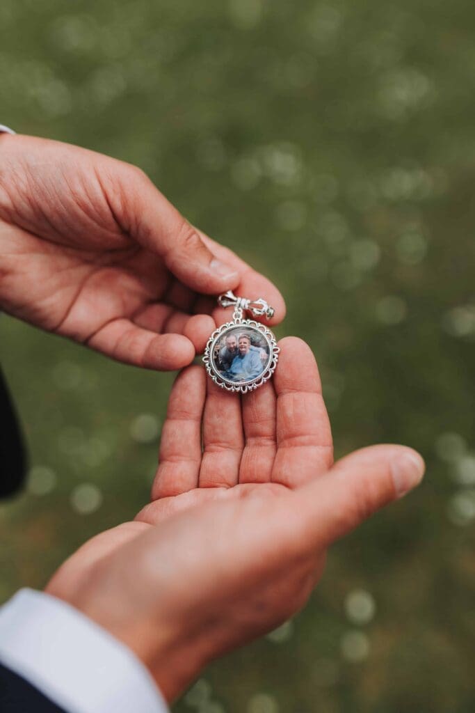 groom holding charm with mums photo in it
