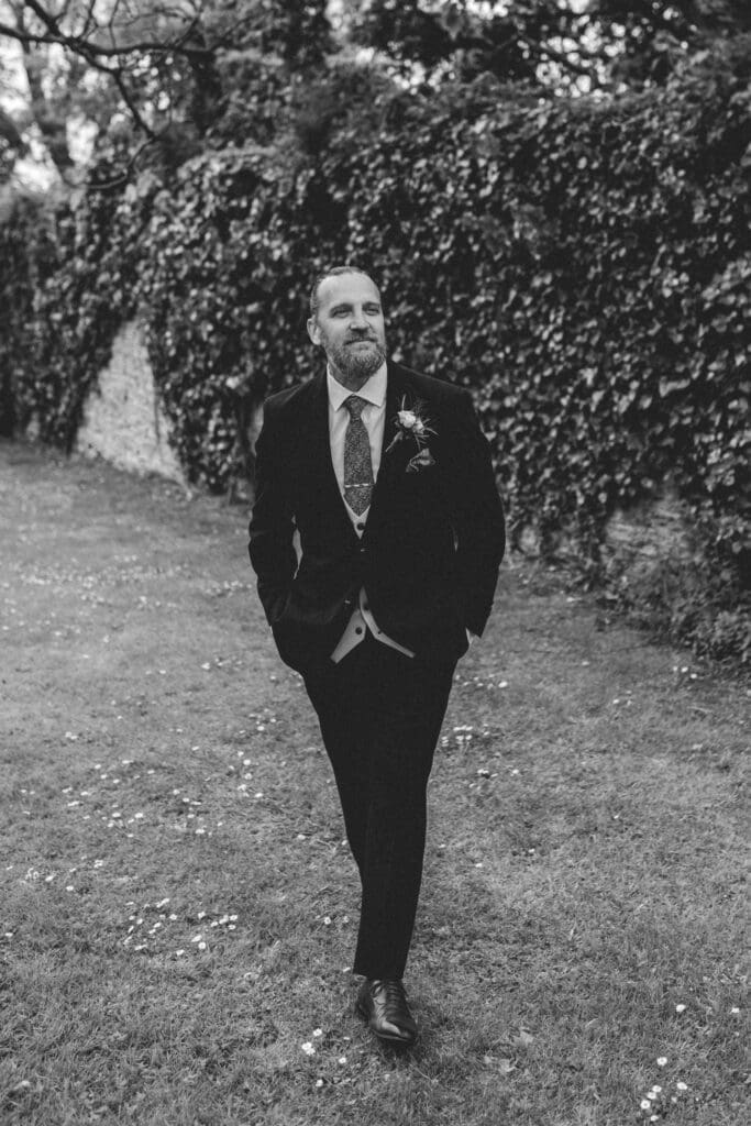 groom walking in cornwall elopement wedding gardens
