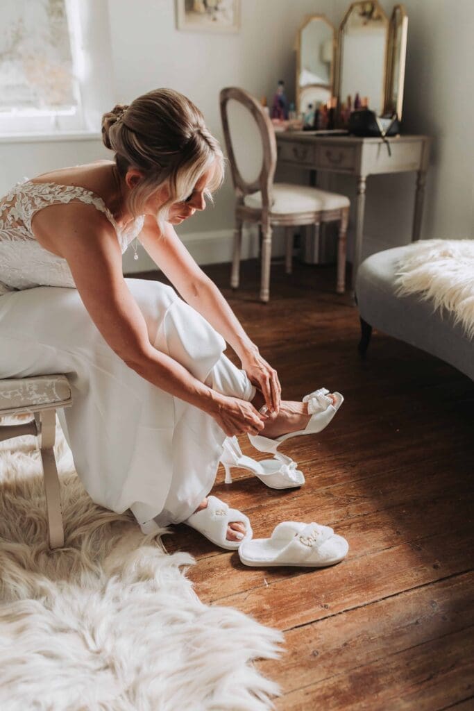 bride putting her shoes on in bridal suite at cornwall elopement wedding