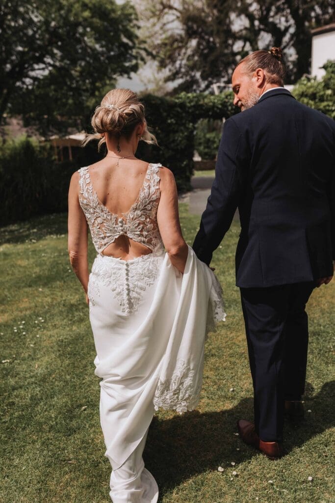 bride and groom walking and groom holding dress