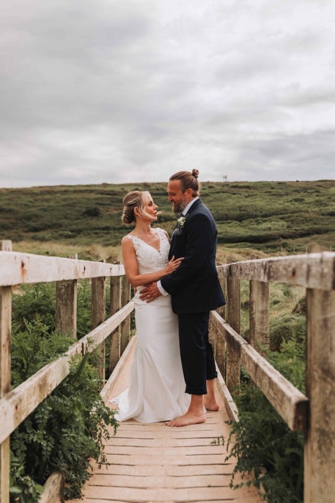 bride and groom on bridge at holywell bay beach