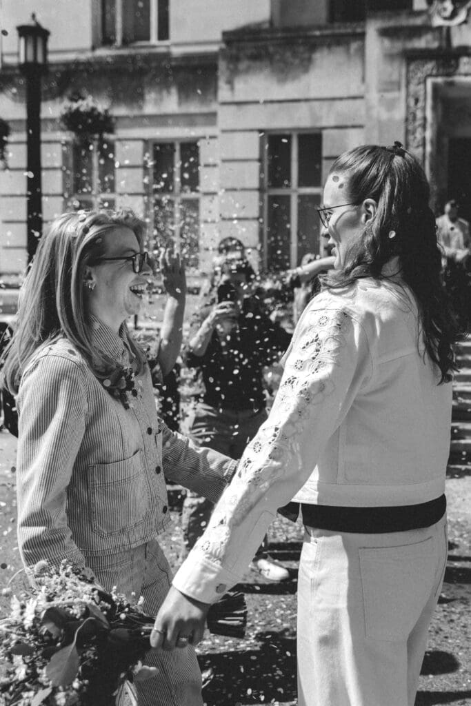 two brides smiling at each other after confetti moment at wandsworth town hall wedding