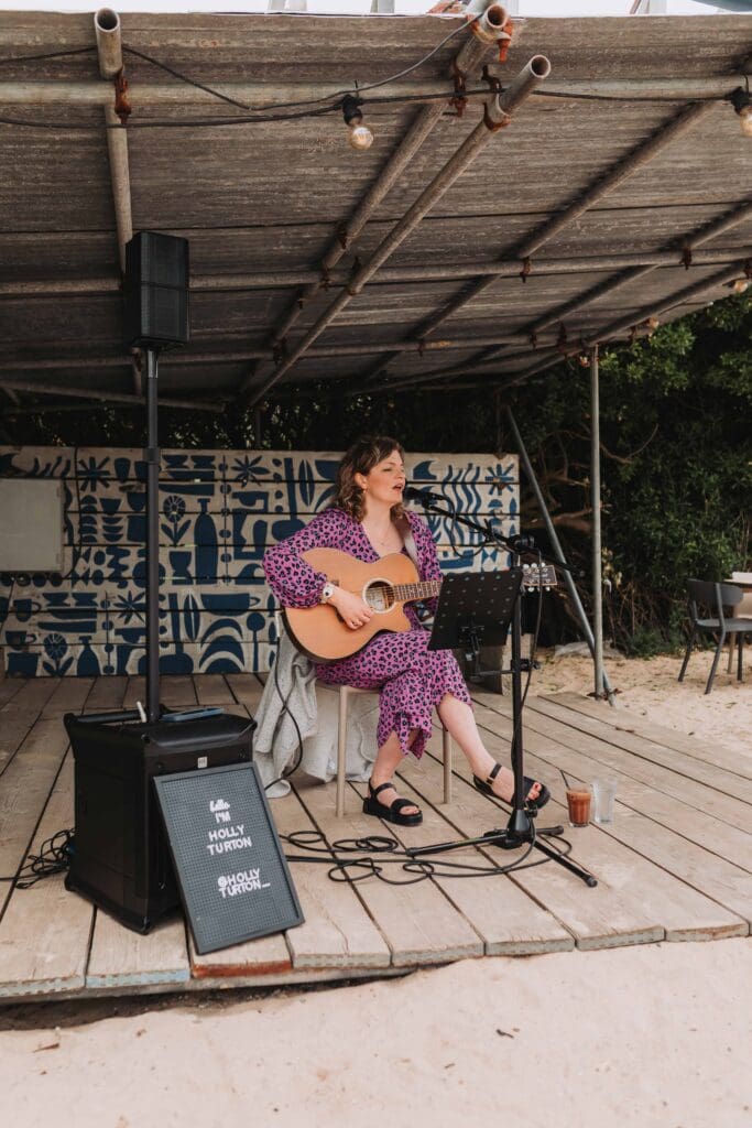 female guitarist singing at beachside venue