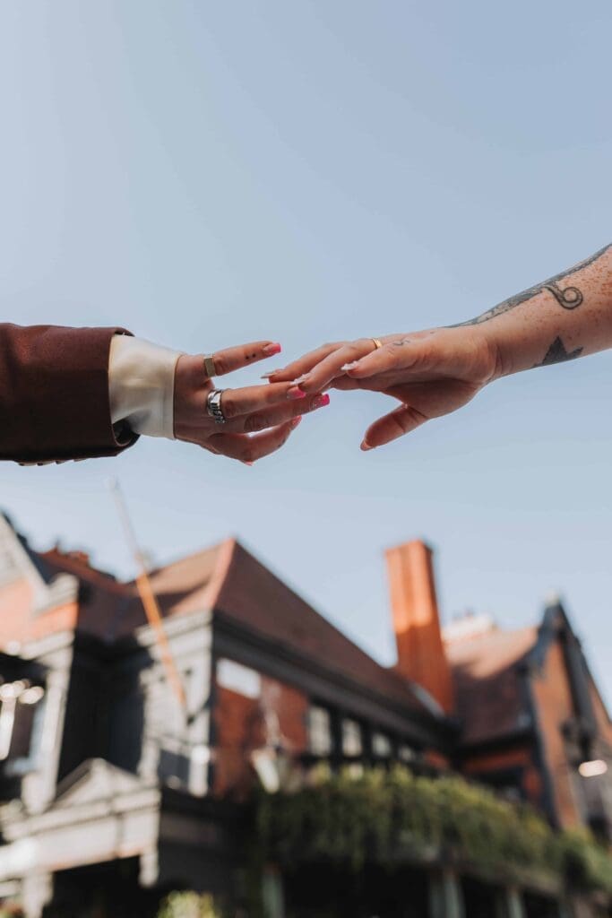 two brides hands reaching out with wedding rings on