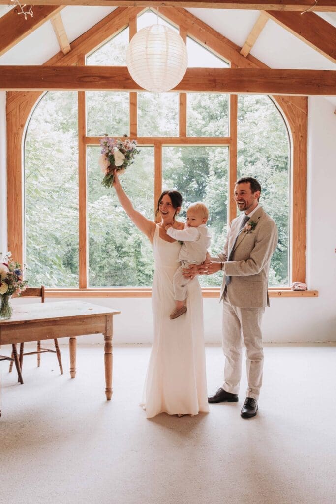 bride holding son next to new husband cheering after ceremony
