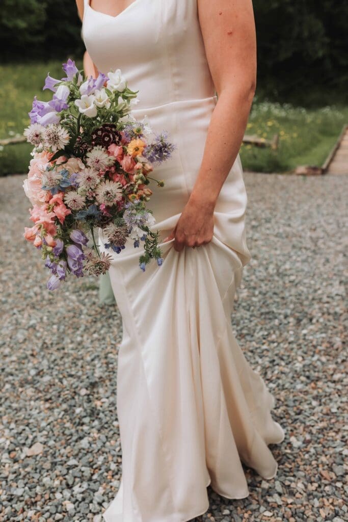 bride holding front of dress and bouquet