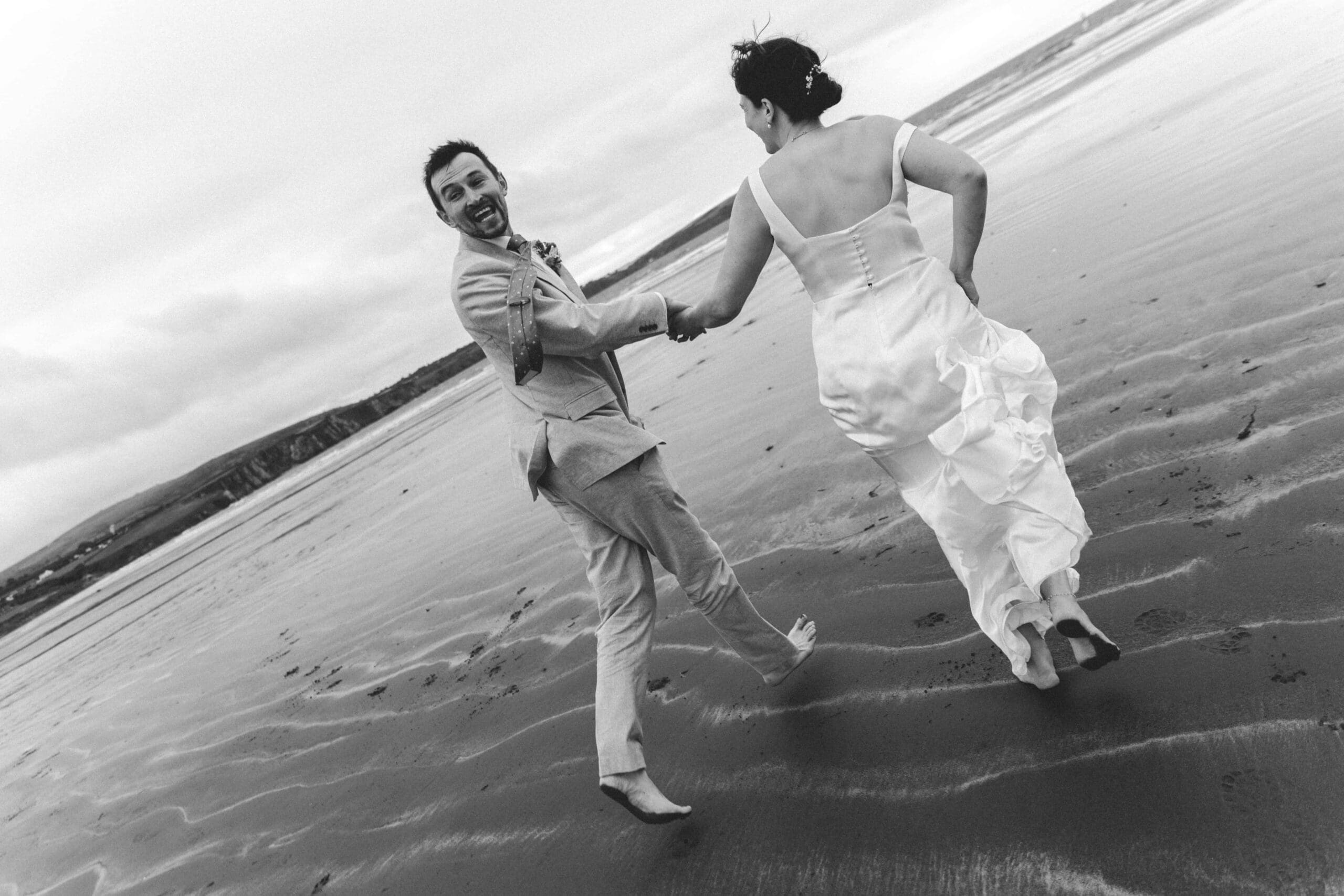 bride and groom running to see and groom looking back