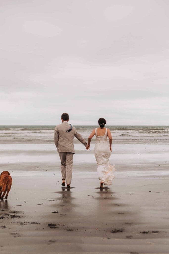 bride and groom and dog running to the sea