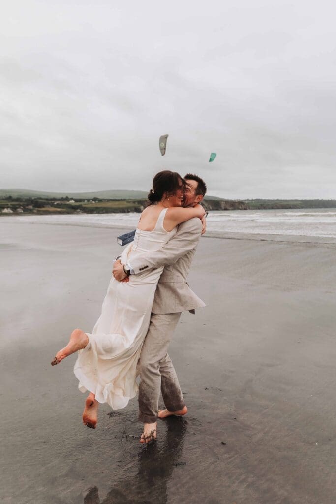 groom swinging bride around on a beach