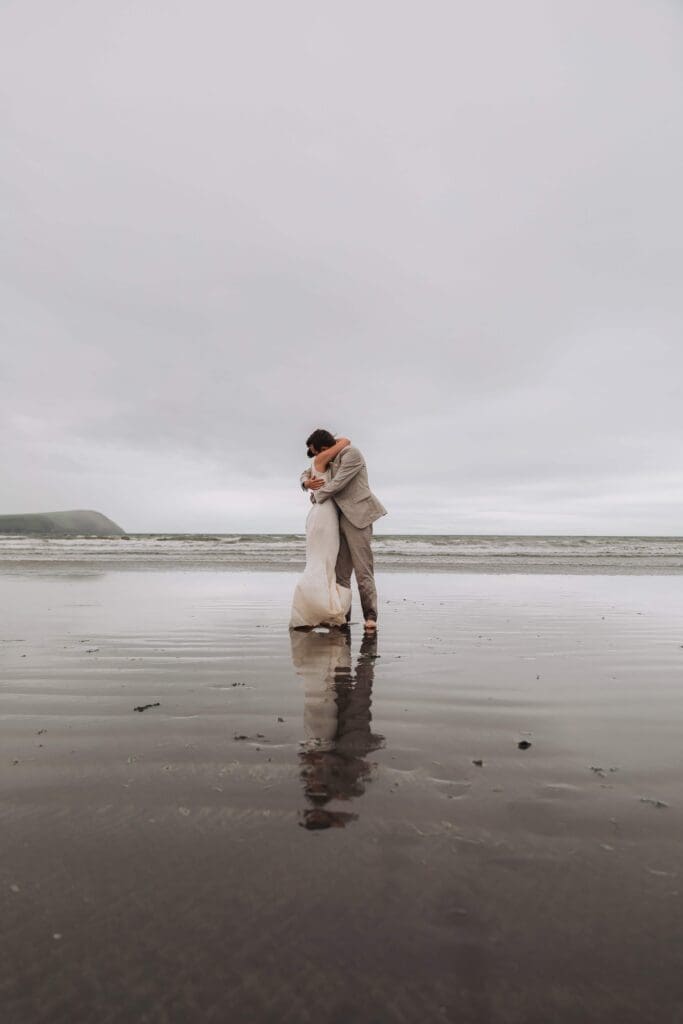 bride and groom holding eachother on beach