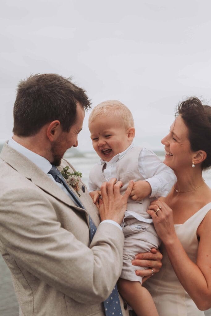 bride and groom cuddling and laughing with son after deciding to elope in the uk