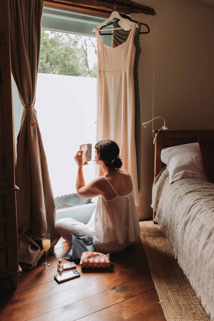 bride doing her makeup in a doorway after deciding to elope in the uk