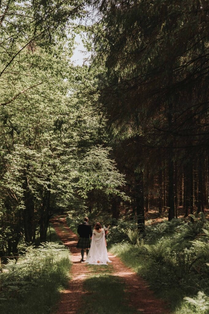 bride and groom walking through woodland