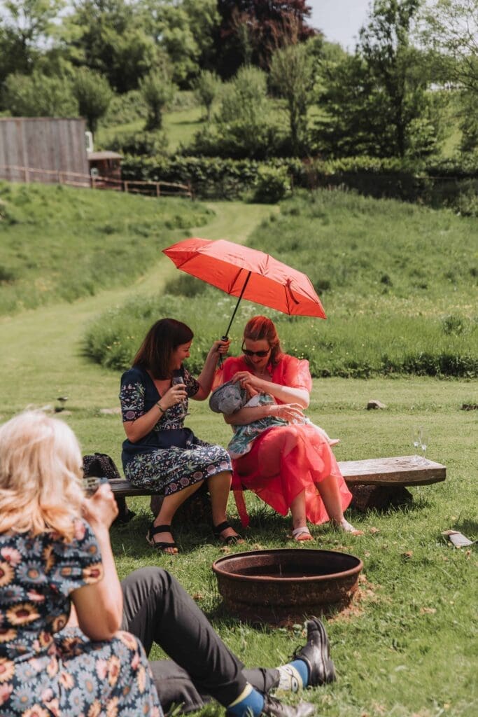 guests sheltering under umbrella at sunny wedding