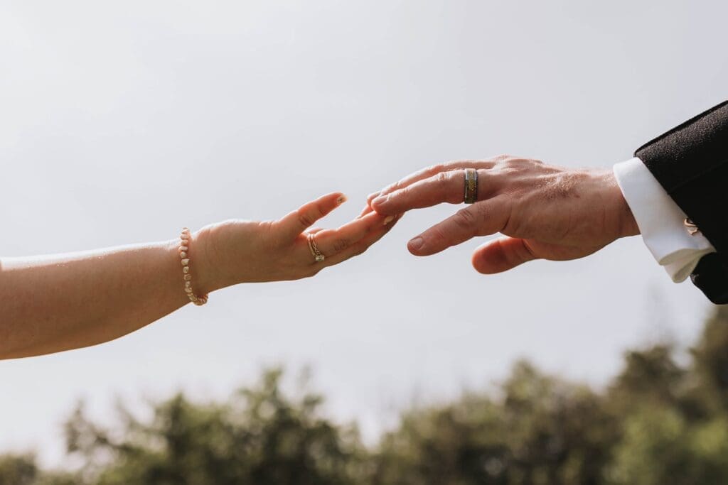 bride and groom reaching hands out to each other