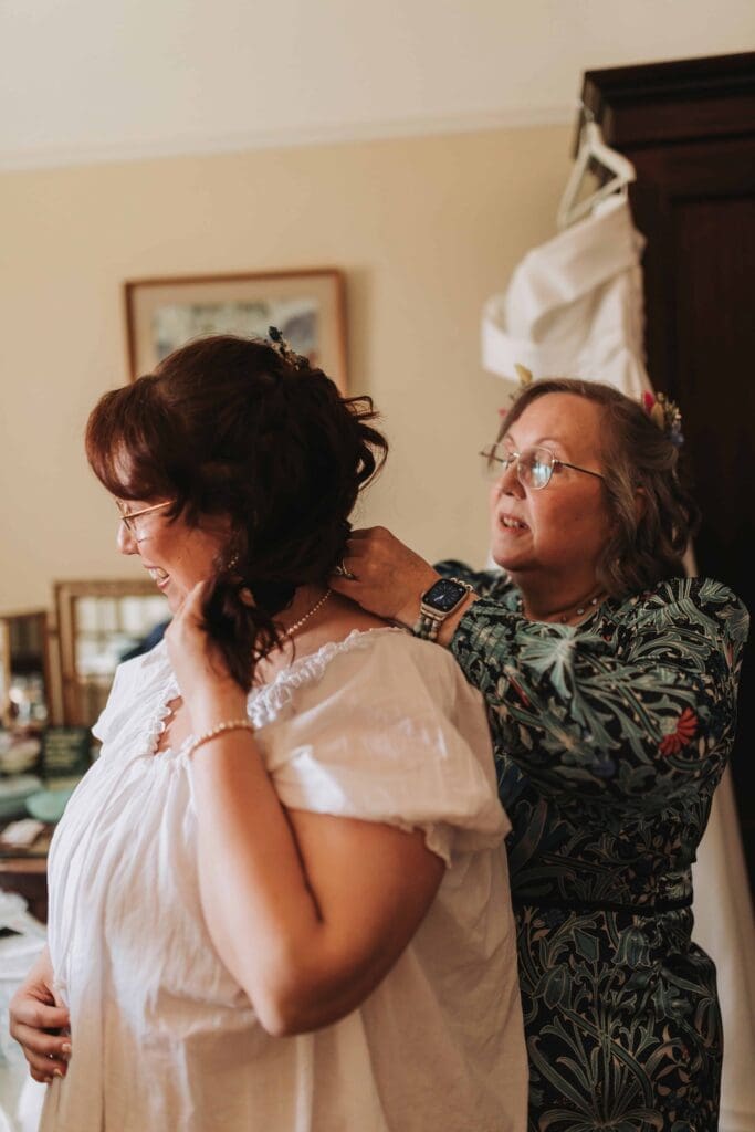 mother of the bride putting necklace on bride