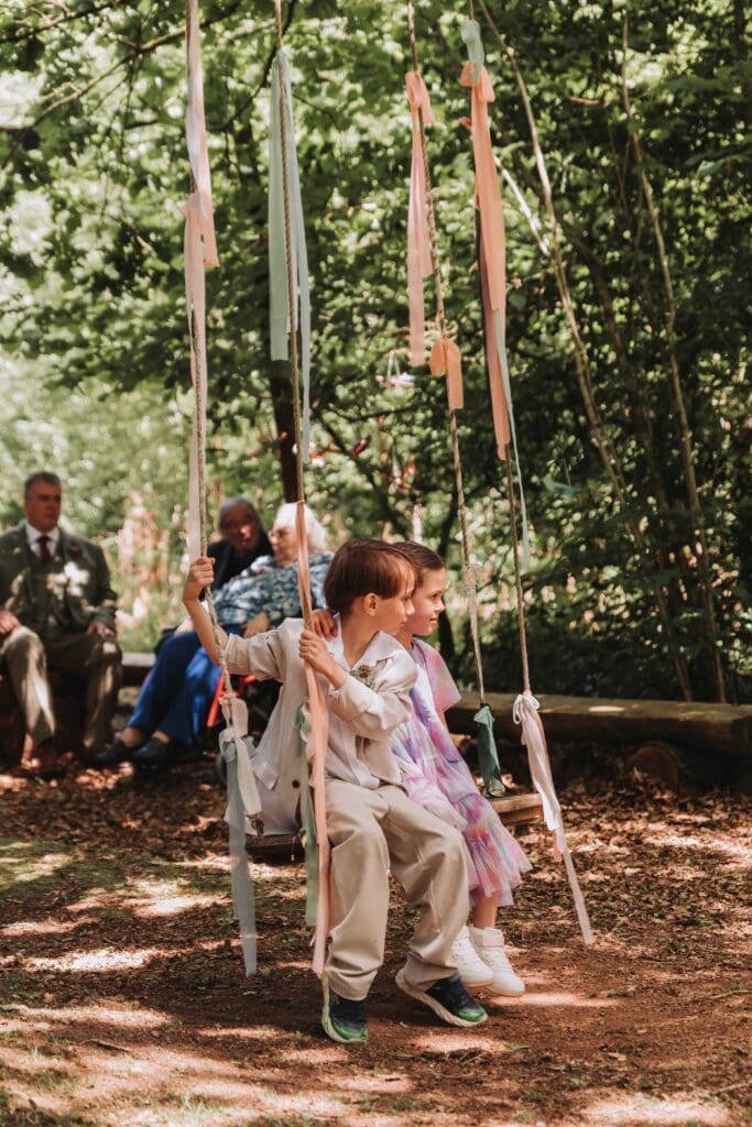 two children on a tree swing at woodland wedding