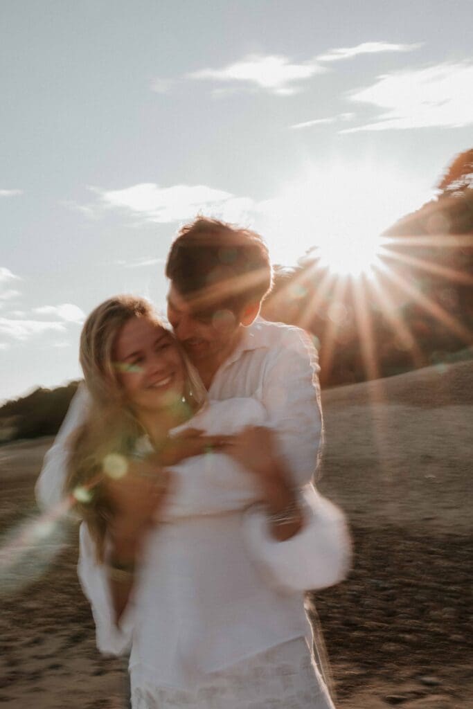 guy hugging girl from behind at beach couple photoshoot