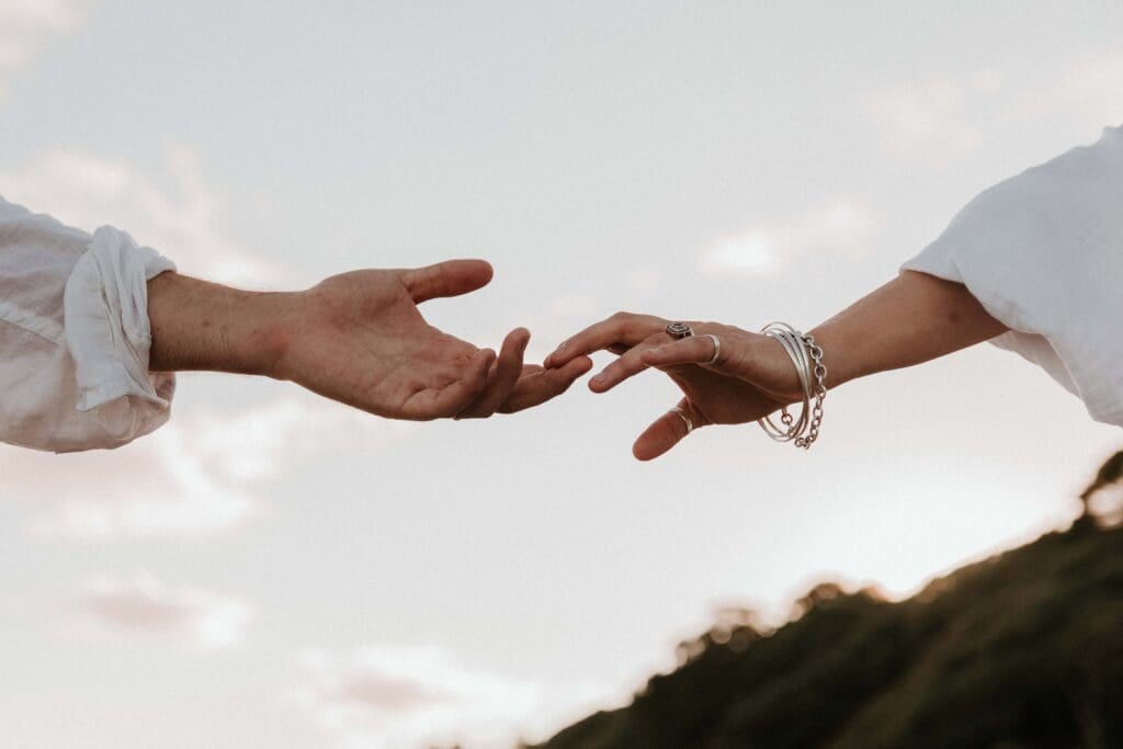 two hands reaching for each other at beach couple photoshoot