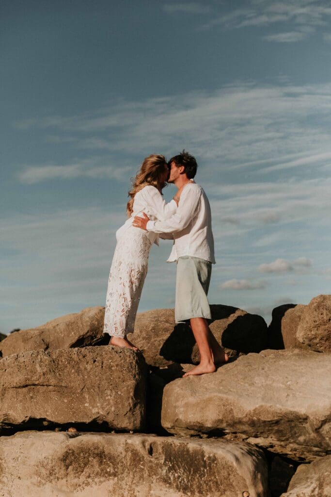 guy and girl kissing on top of rocks