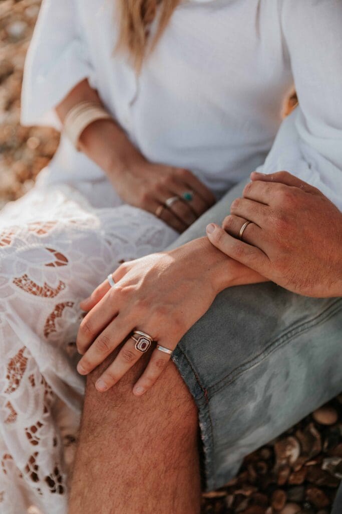 rings on guy and girls hands on hid knee