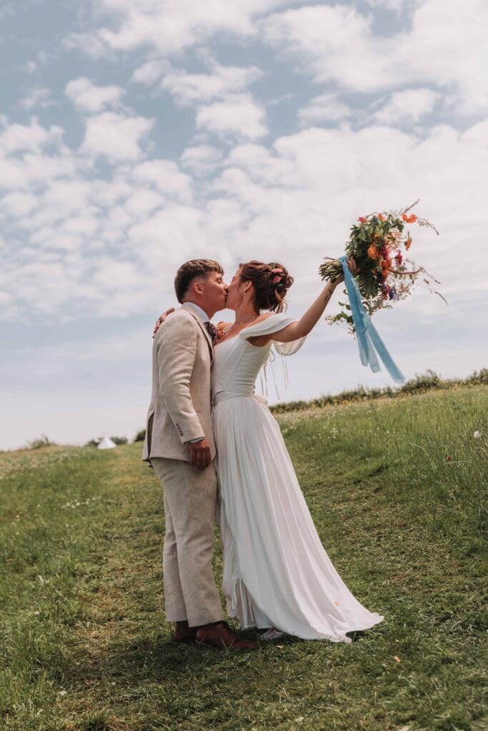 bride and groom kissing with brides bouquet in the air